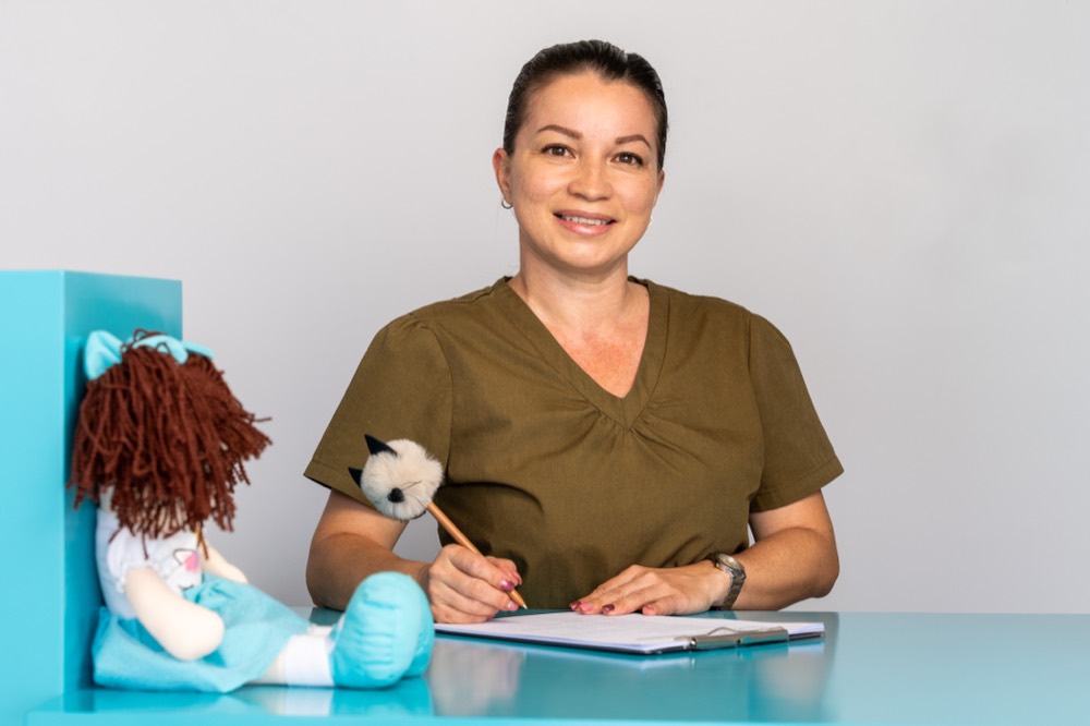 Asistente de la clínica escribiendo junto a una muñeca